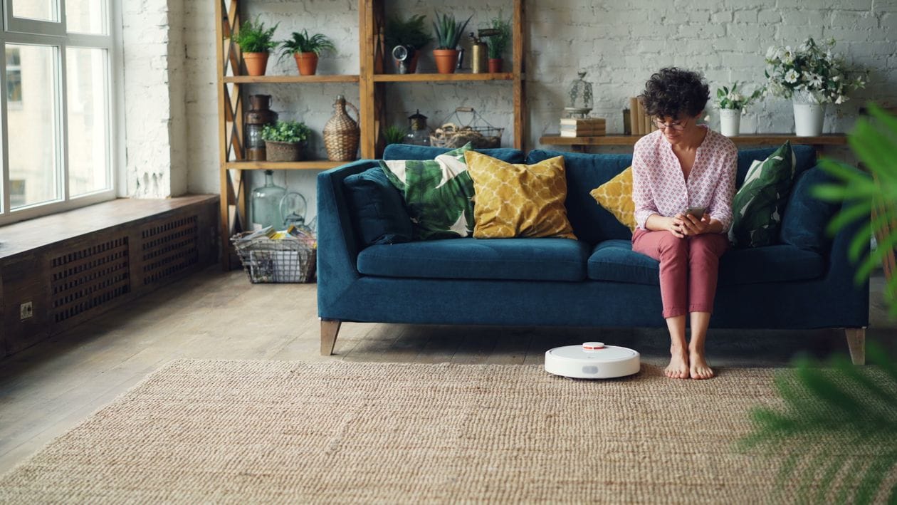 Ruang tamu nyaman dengan robot vacuum dan perangkat smart home