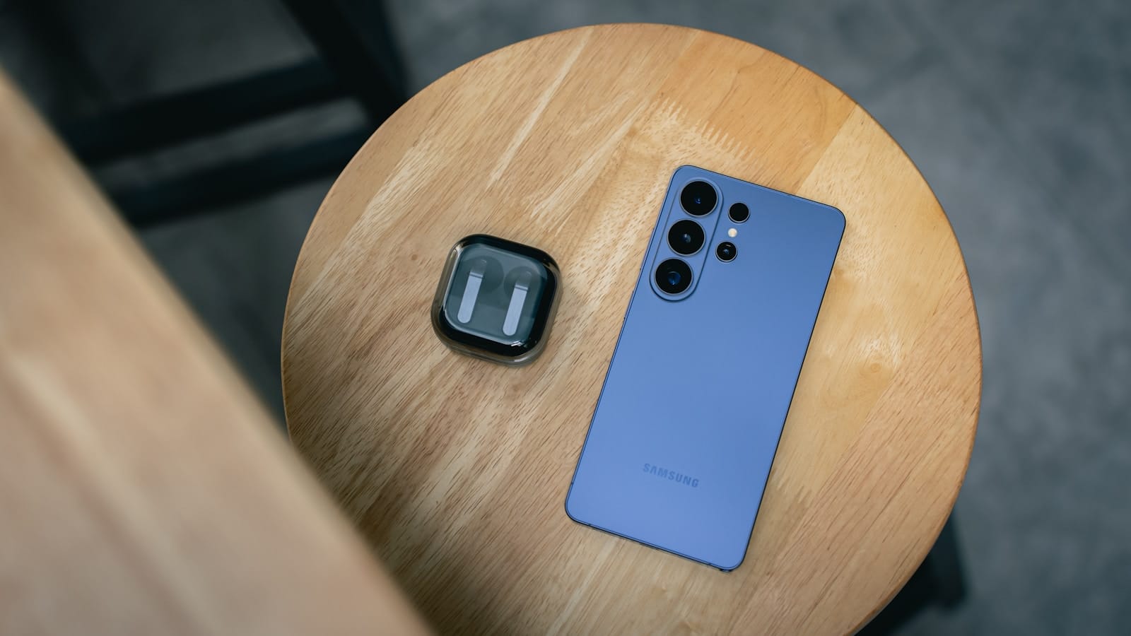 Smartphone Android dan earbuds nirkabel Bluetooth di atas meja kayu